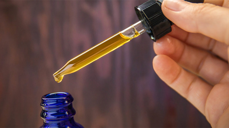 A person taking CBD oil using form bottle using a dropper