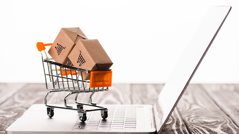 Selective focus of toy shopping cart with boxes on a laptop